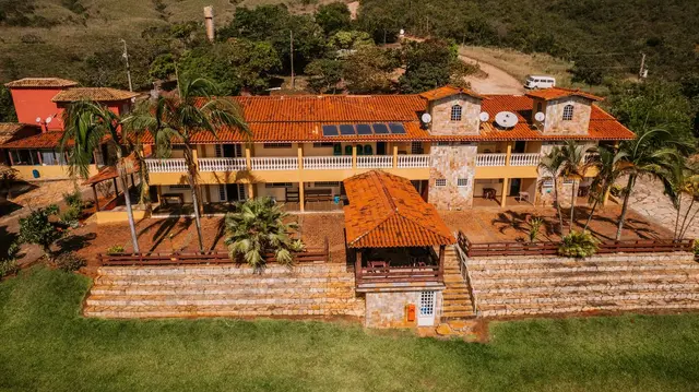 Vista aérea da fachada da Pousada Solar Dona Dora com varandas, palmeiras e quiosque