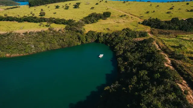 Vista aérea de lancha ancorada em braço calmo do Lago de Furnas cercado por vegetação