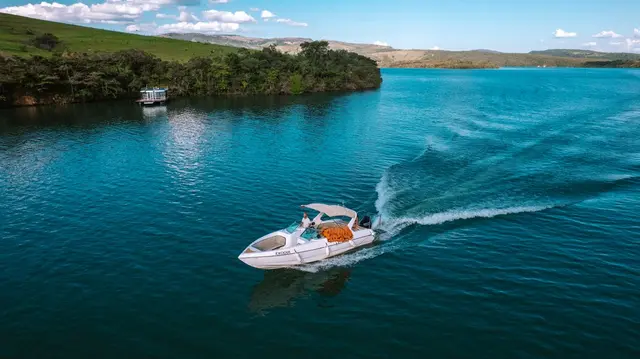 Lancha navegando no Lago de Furnas com deck flutuante ao fundo em Capitólio