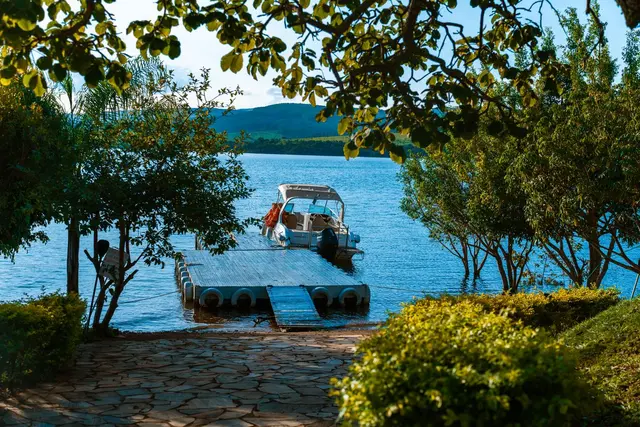 Píer com lancha atracada no Lago de Furnas visto entre as árvores da Pousada Solar Dona Dora