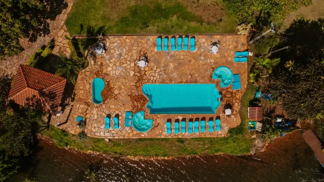 Vista superior da piscina em pedra com espreguiçadeiras e parquinho da pousada
