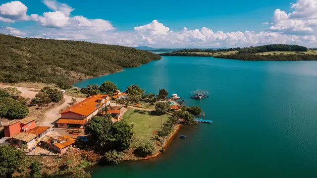 Vista aérea da Pousada Solar Dona Dora às margens do Lago de Furnas sob céu azul em Capitólio