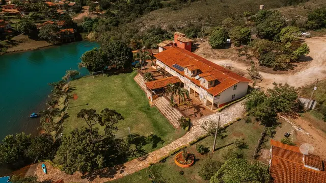 Vista aérea da Pousada Solar Dona Dora com jardim, campo e caiaques às margens da represa