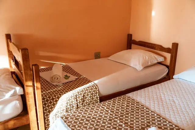 Quarto aconchegante com camas de solteiro e toalhas dobradas na Pousada Solar Dona Dora